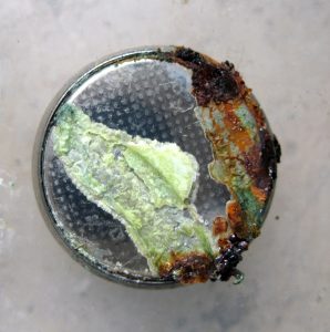 button battery showing green and brown chemical corrosion